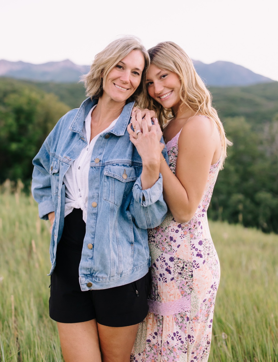 Niki and her daughter Harper smiling together in a mountain meadow