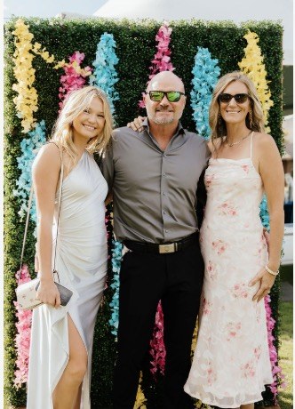 Niki with family in front of a flower wall